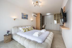 a bedroom with a large white bed with a couch at Villa Verdura in Budva