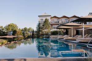 ein Pool in einem Hotel mit Liegestühlen und Sonnenschirmen in der Unterkunft Genussdorf Gmachl - Hotel & Spa in Bergheim