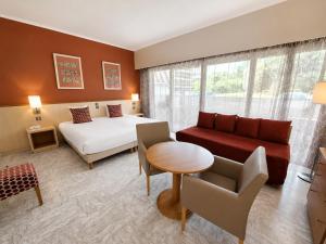 a hotel room with a bed and a couch and a table at The Originals Boutique, Hôtel Les Strélitzias in Juan-les-Pins +50 photos