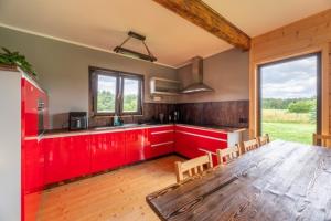a kitchen with red cabinets and a large wooden table at Leśny Wyraj in Borsuki