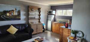 a living room with a couch and a kitchen at Volgenoeg Self Catering Cottage in Oudtshoorn
