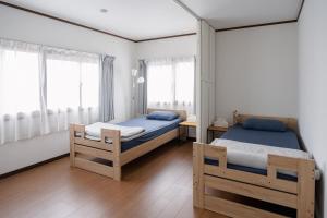 a bedroom with two beds and two windows at Kaga Travel - Hakusandai, Whole building for rent in Kaga
