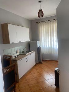 a kitchen with white cabinets and a sink and a table at Marina View in Shëngjin