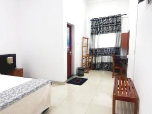 a bedroom with a bed and a chair and a window at Mount View Hotel Badulla Room 02 in Badulla
