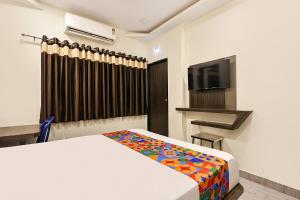 a hotel room with a bed and a television at FabHotel Happy in Vijayawāda