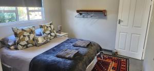 a bedroom with a bed with pillows on it at Volgenoeg Self Catering Cottage in Oudtshoorn