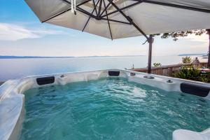 a hot tub with an umbrella next to the water at SUPER HORIZONT- Sea View Apartments with private Jacuzzi time & Free Parking in Split