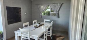 a dining room with a white table and chairs at Volgenoeg Self Catering Cottage in Oudtshoorn +17 photos
