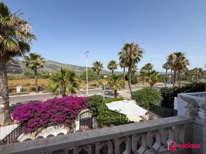 a balcony with purple flowers and palm trees and a street at Bloom House in Oropesa del Mar