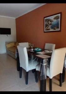 a dining room table with white chairs and a couch at Departamentos Maxx II in Colón