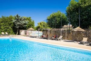 a swimming pool with people sitting in chairs next to it at Camping Sud Ardèche 3 étoiles familial piscine chauffée Gorges de l Ardèche Saint Remèze in Saint-Remèze