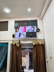 a tv on the wall in a room with curtains at Dhanwantri Niwas in Varanasi