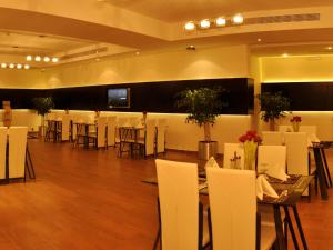 Salón de banquetes con sillas y mesas blancas y TV en Nelover Qurtubah Hotel en Riad