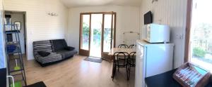 a living room with a refrigerator and a table with chairs at Chalet confort 2 piscine partagée in Les Vans +10 photos