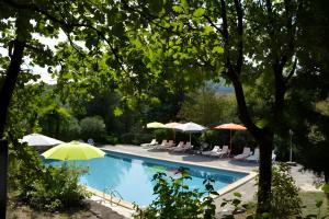a swimming pool with umbrellas and chairs at Chalet confort 2 piscine partagée in Les Vans