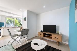a living room with a tv and a table at Aybowan - Jacuzzi - Climatisation in Les Avirons +7 photos