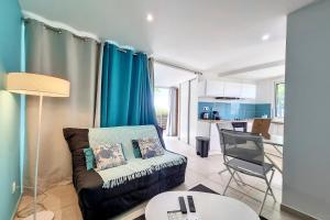 a living room with a couch and a table and a kitchen at Aybowan - Jacuzzi - Climatisation in Les Avirons