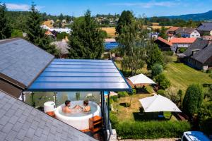 zwei Personen in einer Badewanne im Garten in der Unterkunft Hotel Tommy Wellness & Spa in Náchod