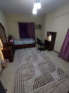 a bedroom with a bed and a rug on the floor at ابراهيم هاوس in Al Ghuşnah
