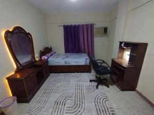 a bedroom with a bed and a desk and a mirror at ابراهيم هاوس in Al Ghuşnah