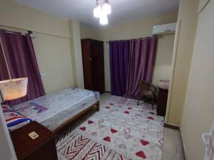 a bedroom with a bed and a room with purple curtains at ابراهيم هاوس in Al Ghuşnah