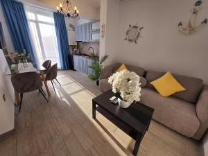 a living room with a couch and a table with flowers at Alezzi Luxury Double Studio - Beach Pool & Spa Resort in Mamaia Sat/Năvodari