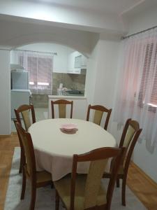 ein Esstisch mit Stühlen, ein weißer Tisch und eine Küche in der Unterkunft Bane apt in Kravlja