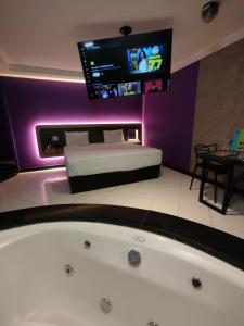 a bathroom with a tub and a bed and a tv at iLi Motel in Aparecida de Goiânia +21 photos