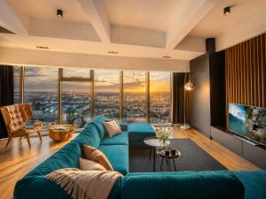 a living room with a blue couch and large windows at Apartamenty Sky Tower in Wrocław