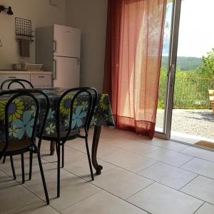 a kitchen with a table and two chairs and a door at Les Lilas piscine partagée in Les Vans