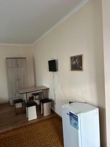 a room with a table and a table and a refrigerator at Достук in Bosteri