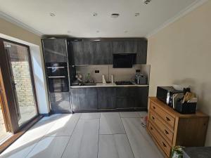 a kitchen with wooden cabinets and a counter top at Prime's Home in Nevendon