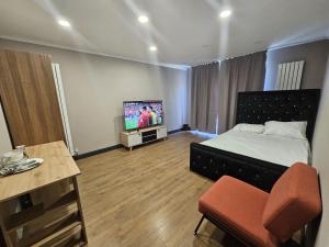 a bedroom with a bed and a tv and a chair at Prime's Home in Nevendon