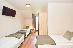 a room with two beds and a tv on the wall at Rancho Adama - wypoczynek w sercu Beskidów! in Pewel Ślemieńska