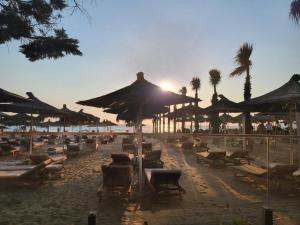 a beach with a lot of chairs and umbrellas at Ibra apartament in Golem