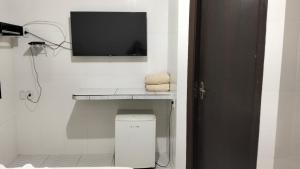 a bathroom with a tv on a white wall at Delta Hotel Nova Mutum in Nova Mutum