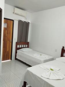 two beds in a white room with a door and a room with twothirdsessions at Delta Hotel Nova Mutum in Nova Mutum