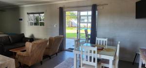 a living room with a glass table and chairs at Volgenoeg Self Catering Family Unit in Oudtshoorn