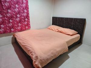 a bed with an orange comforter in a room at AymanSyahir in Mukah