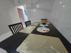 a dining room table with two chairs and a table with flowers on it at AymanSyahir in Mukah +1 photo