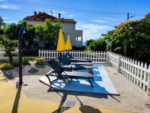 three lounge chairs with yellow umbrellas and a fence at Holiday home Brseč in Mošćenička Draga