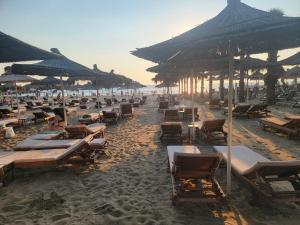 a beach with lots of chairs and umbrellas at Ibra apartament in Golem