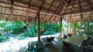 a patio with a table and chairs under a straw umbrella at Guarumbo in Bacalar +26 photos