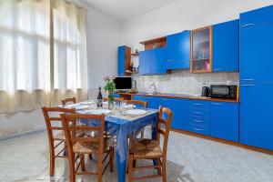 a kitchen with blue cabinets and a table with chairs at Villa Anny in Avola