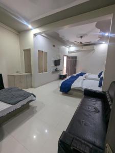 a large room with two beds and a couch in it at Hotel MJ in Ujjain
