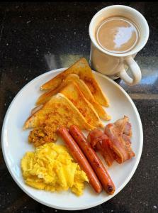 a plate with eggs bacon and toast and a cup of coffee at De Lexury Homes in Otinshi