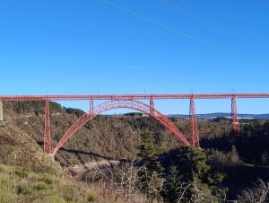 a large red bridge in the middle of a hill at Domaine du Viaduc in Garabit