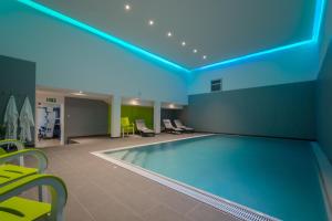 a pool in a hotel room with yellow chairs and a blue ceiling at Hotel Fortuna in Schwäbisch Gmünd