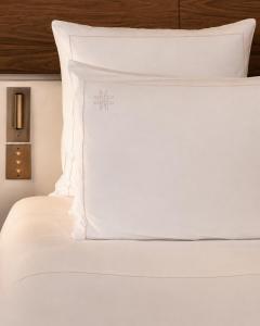 a white bed with white sheets and pillows at Hotel Le Morgane in Chamonix