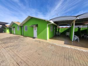 a green building with tables and chairs in a courtyard at Condomínio Gold in Três Lagoas